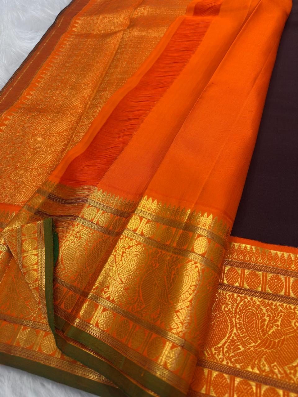 Close view of gold zari Mayil buttas woven across deep brown Kanchipuram silk.
