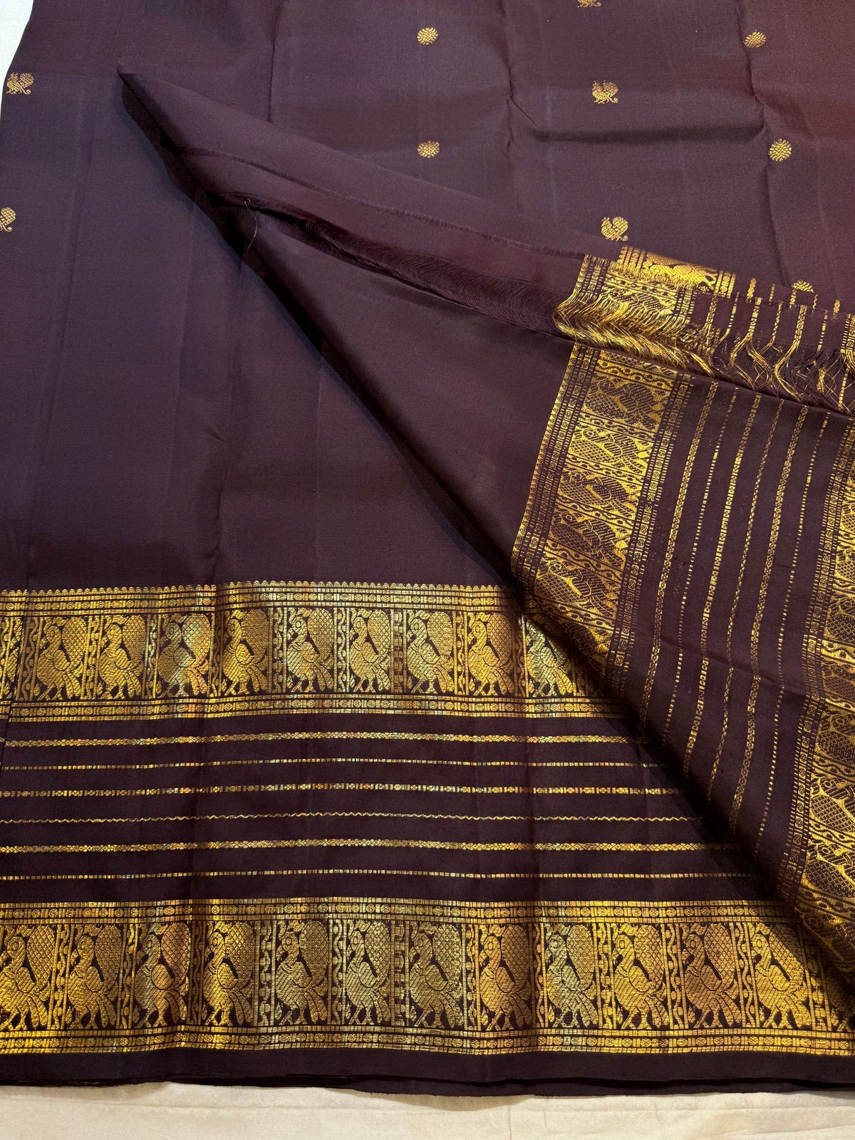 Dark brown Kanchipuram Varisaipet saree with spaced antique-gold zari motifs and richly woven bird border.