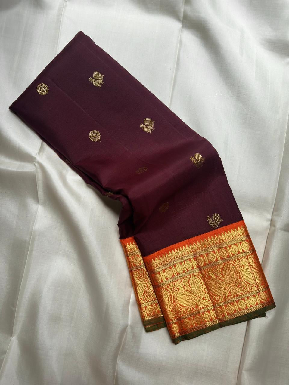Deep Kanchana Brown silk body with individually woven gold zari Mayil and circular buttas.
