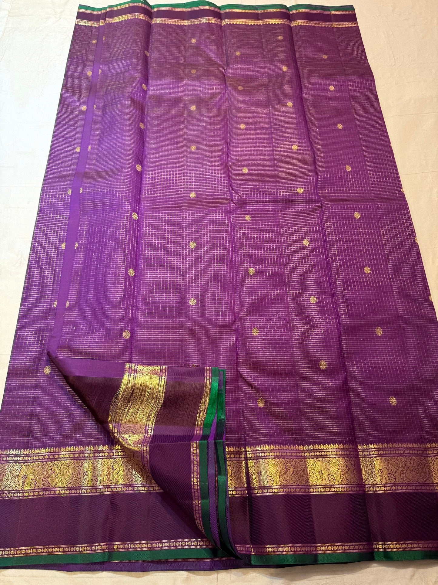 Folded Kanchana Purple Zari Kattam saree showing ornamental gold zari border.