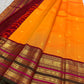 Bright marigold orange Kanchipuram silk saree with gold buttas and deep red ornate Varisaipet border.