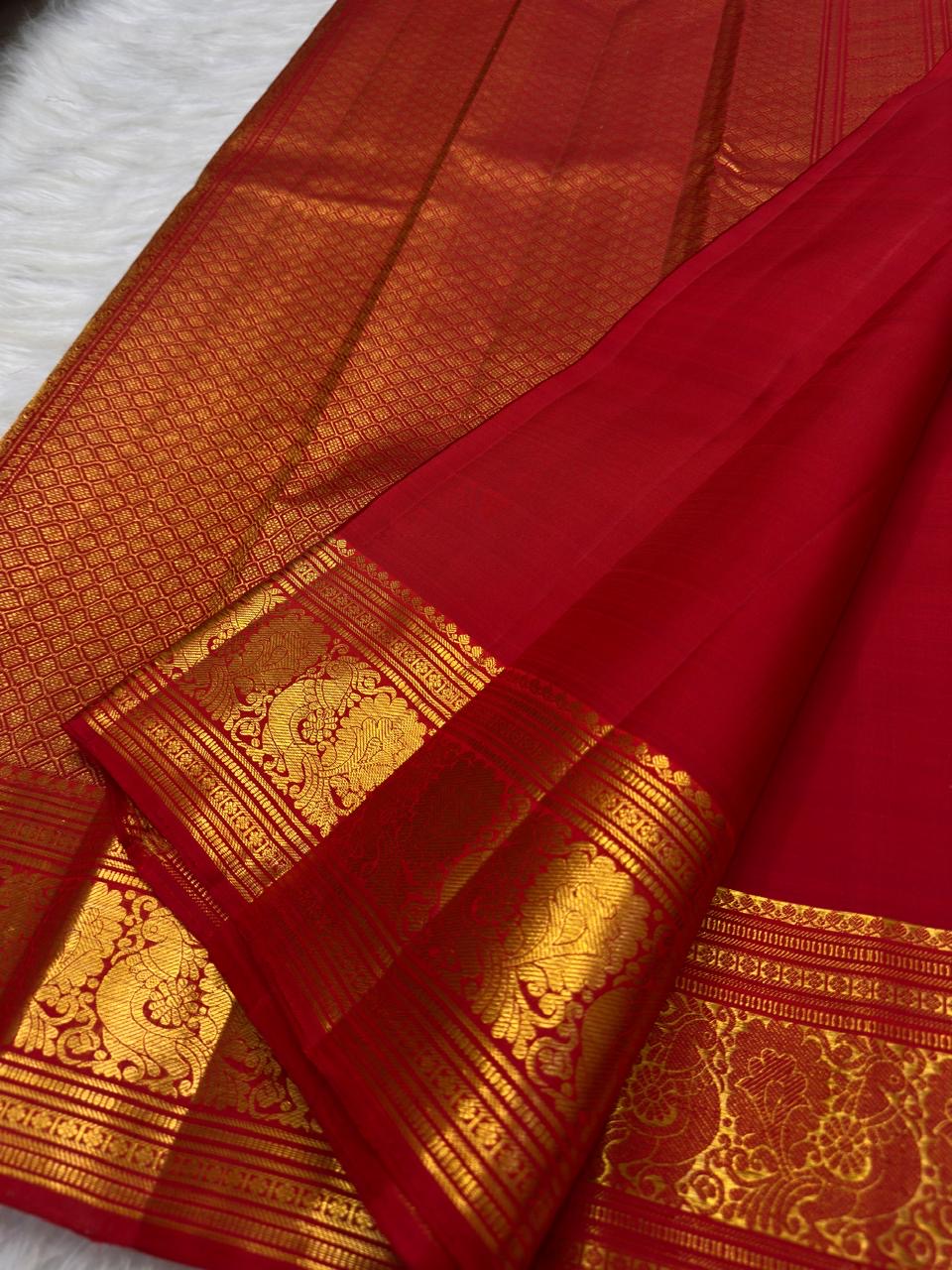 Vermilion red, warm Arakku-red undertones and rich yellow gold handwoven Kanchipuram butta silk saree, border zari detail, with gold zari detailing.