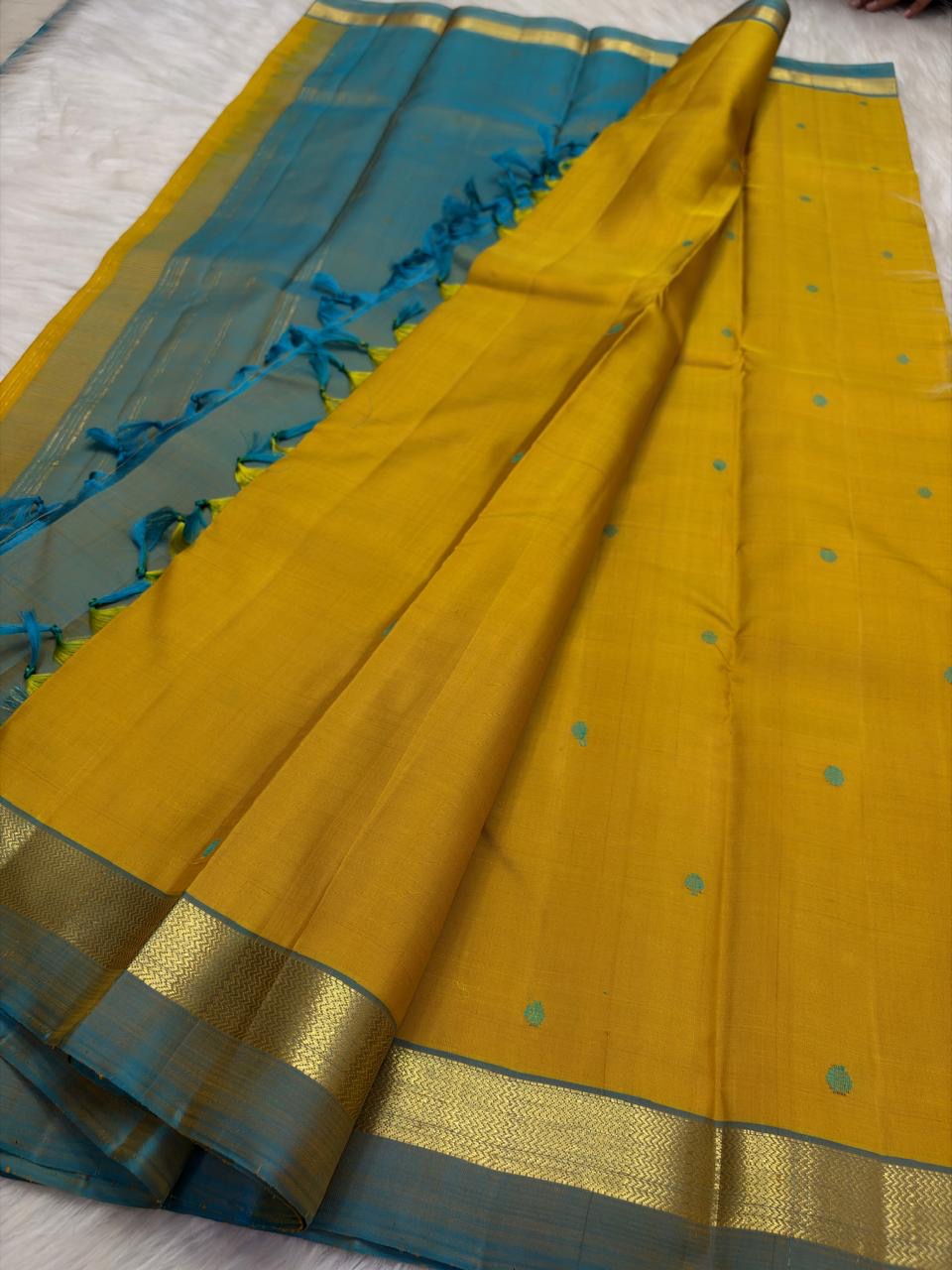 Turmeric yellow Pure Kanchipuram Silk saree with peacock blue pallu, slim gold zari border and delicate teal buttas