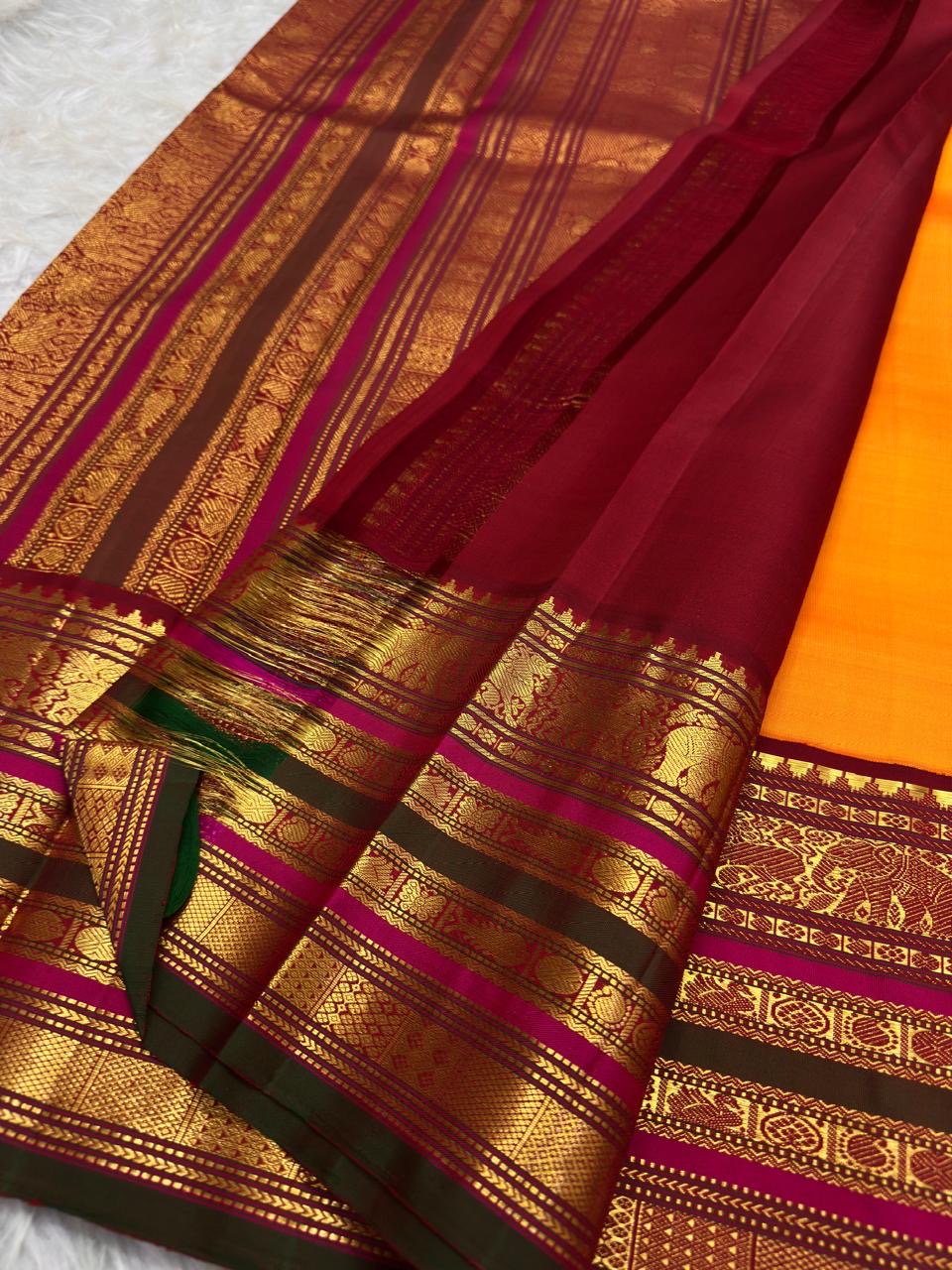 Marigold orange Kanchipuram silk saree body with gold buttas.