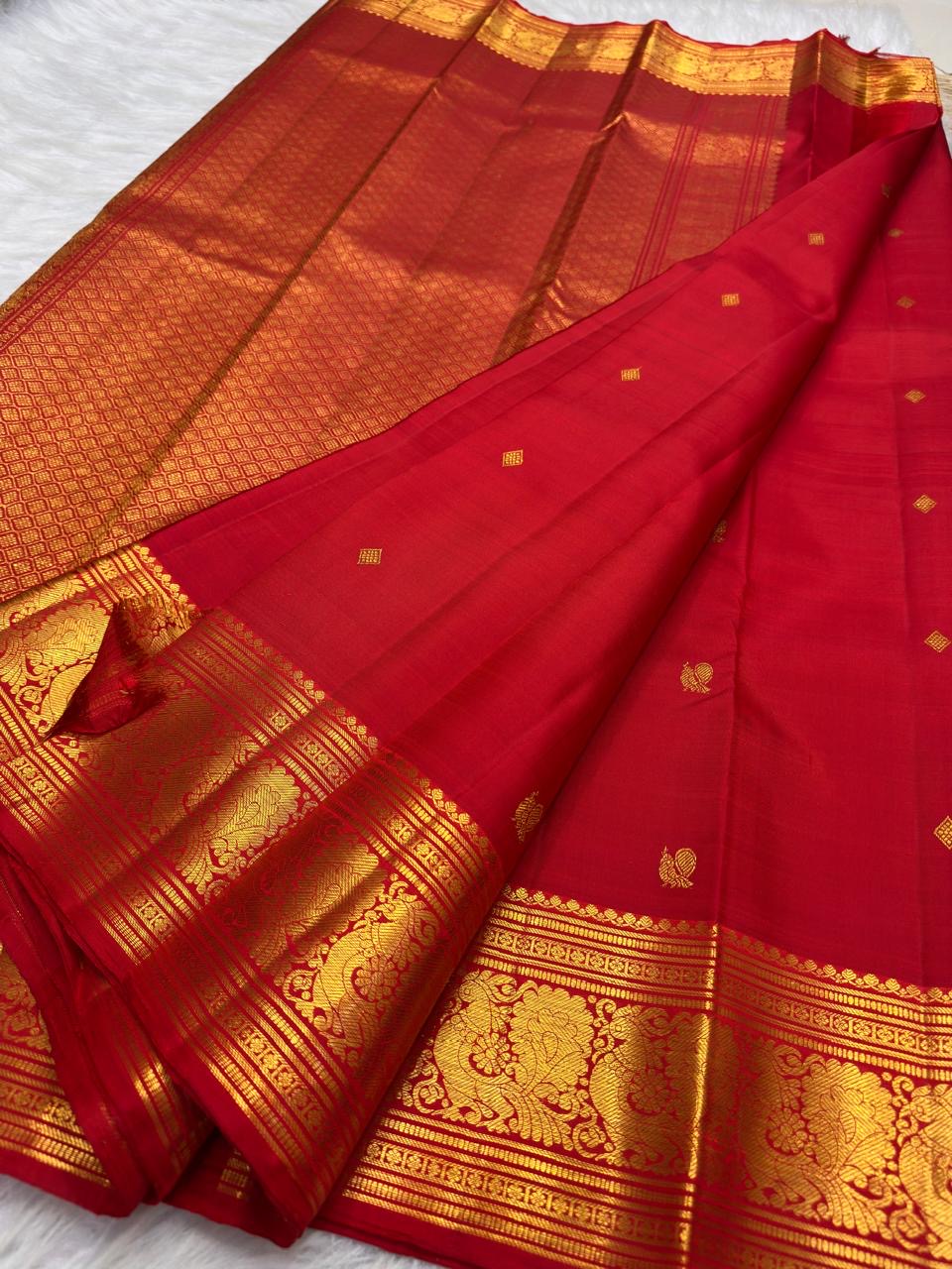 Vermilion red, warm Arakku-red undertones and rich yellow gold handwoven Kanchipuram butta silk saree, unfolded full view, with gold zari detailing.
