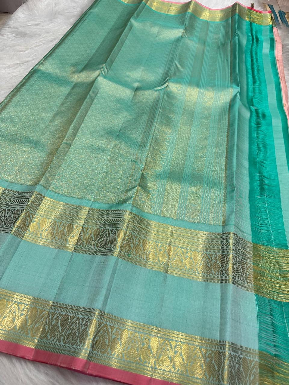 Close-up of antique gold zari buttas on blush rose Kanjivaram silk saree body