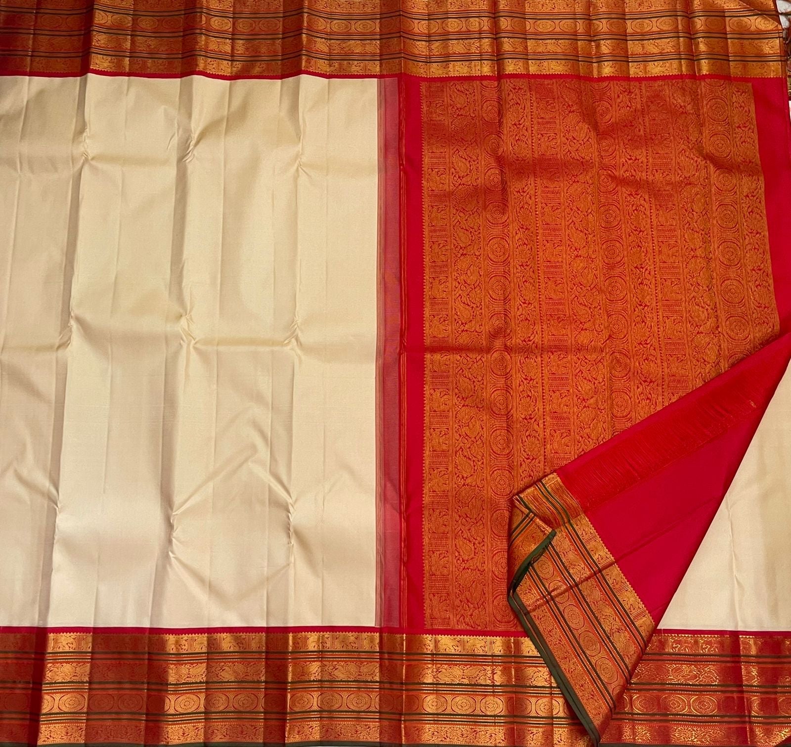 Flat-lay ivory pure Kanchipuram silk saree with rich red zari woven pallu and border, shipped from New Jersey USA.