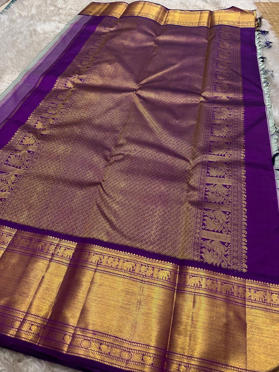 Spread purple pallu with gold zari detailing framed by a wide purple border and zari panels
