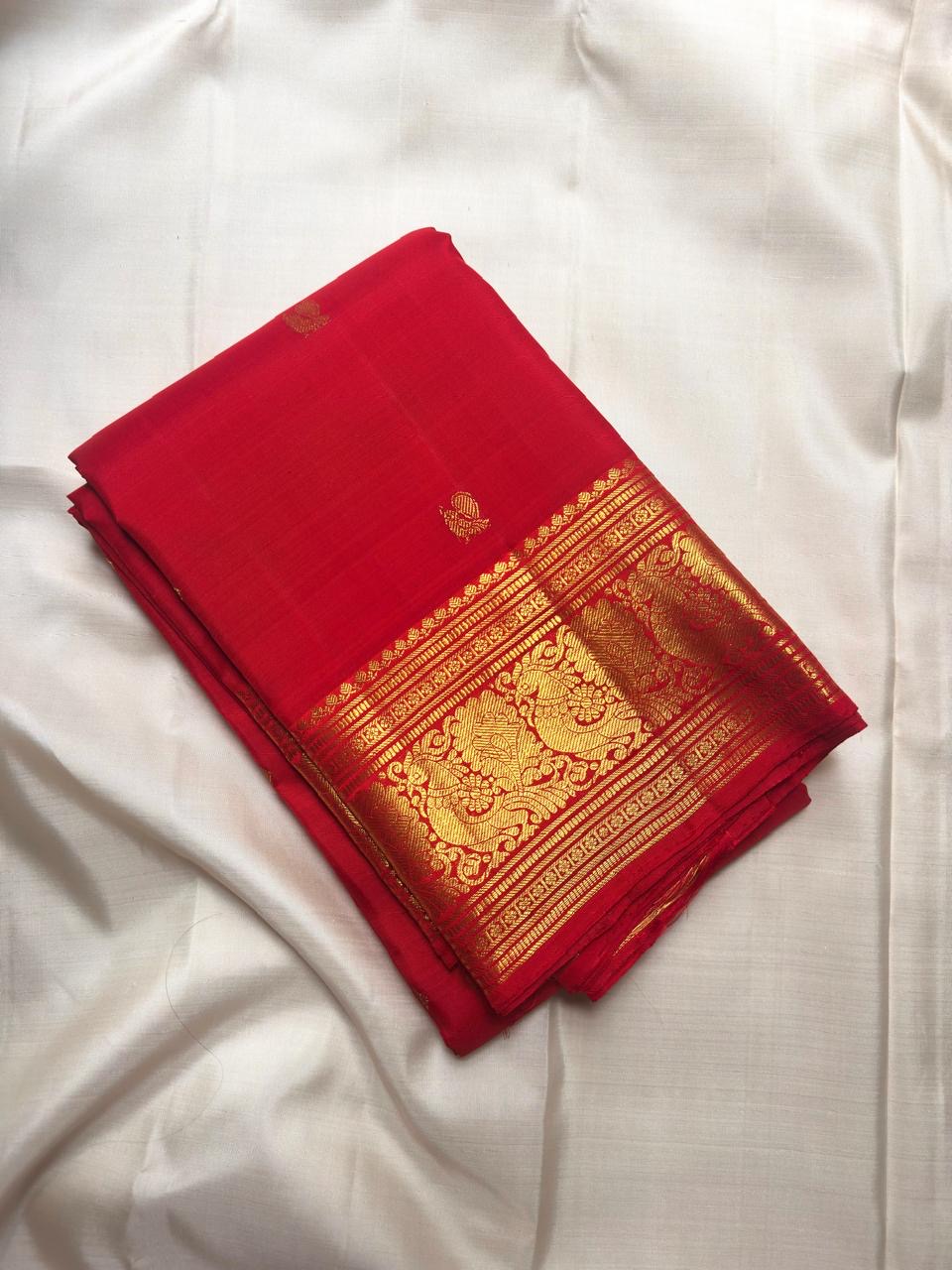 Vermilion red, warm Arakku-red undertones and rich yellow gold handwoven Kanchipuram butta silk saree, body silk detail, with gold zari detailing.