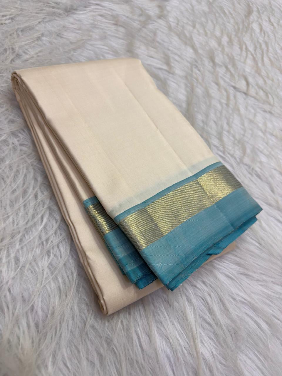 Warm ivory Pure Kanchipuram Silk saree with Firozi blue narrow border and softly gleaming gold-toned zari pallu