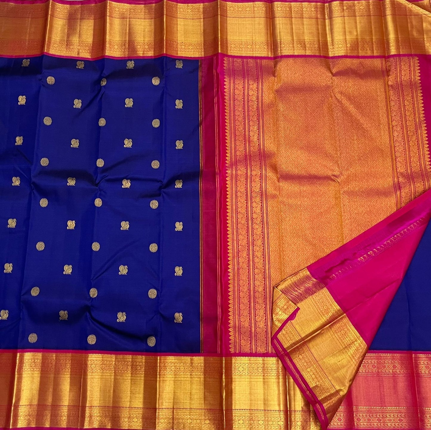 Blue Kanchipuram silk saree with gold zari buttas, wide gold zari border, and pink edge beside a gold zari pallu section.
