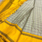 Kanchipuram silk saree spread showing checked body, mustard zari border, and mustard pallu with tassels