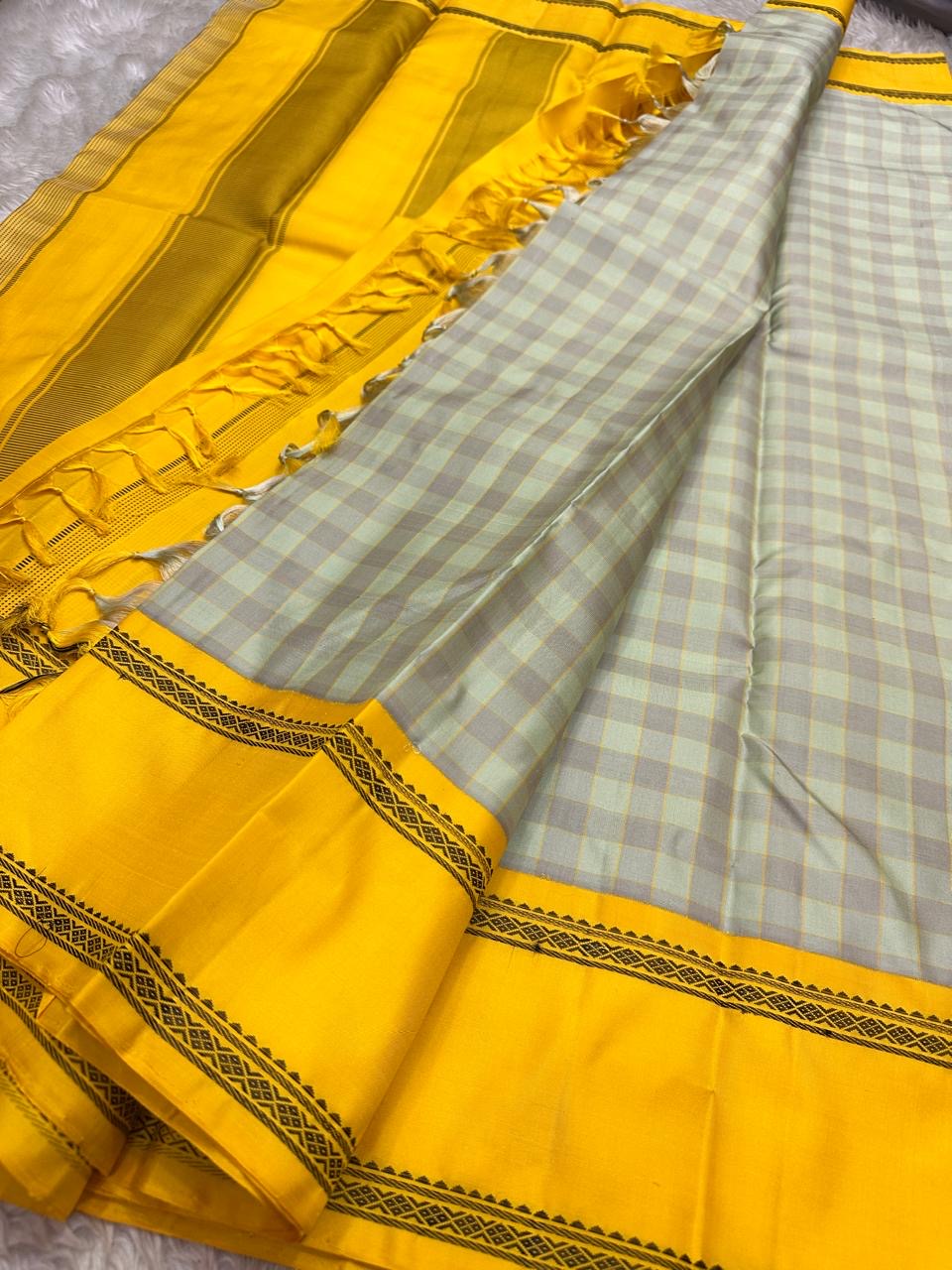 Kanchipuram silk saree spread showing checked body, mustard zari border, and mustard pallu with tassels
