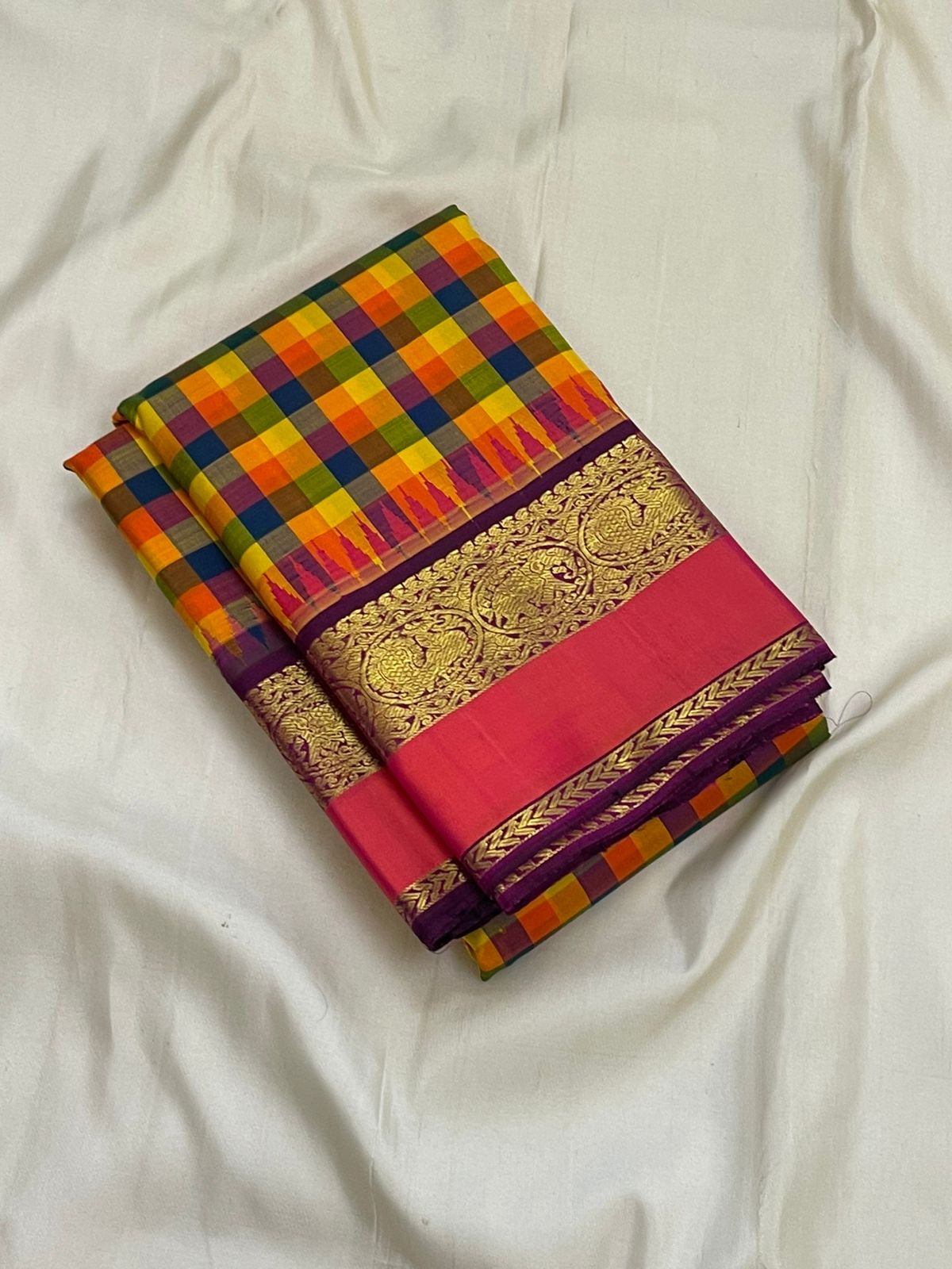 Folded pure Kanchipuram silk saree with multicolor checked body and purple border featuring gold zari weaving