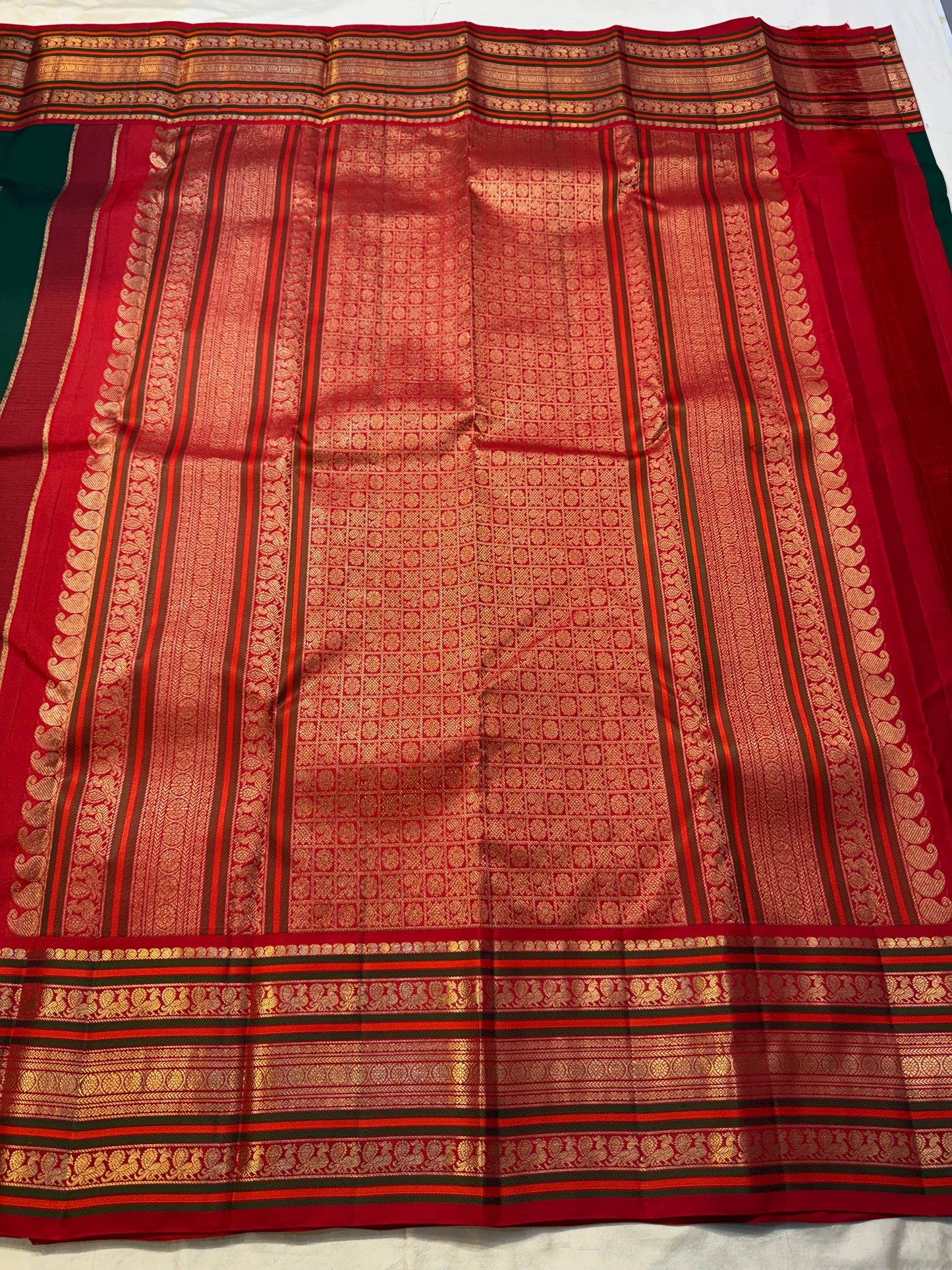 Close-up of chili red varisaipet border and gold zari pallu detail on deep green Kanchipuram silk saree — Idam Living