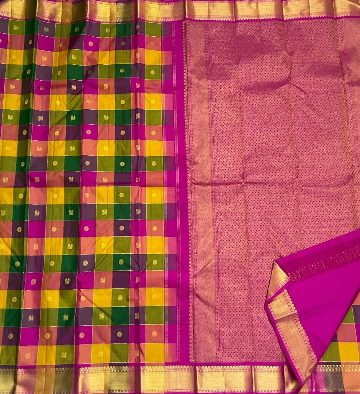 Draped view of checked Pure Kanchipuram silk saree with zari woven gold border and magenta tassels near the pallu.