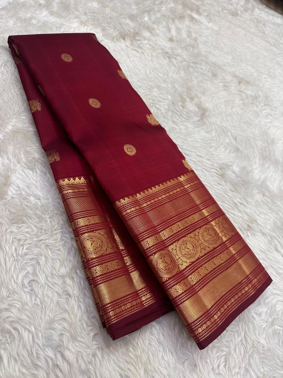 Arakku red pure silk Kanchipuram saree with antique gold mayil chakram buttas and a detailed peacock and arai maadam pallu.