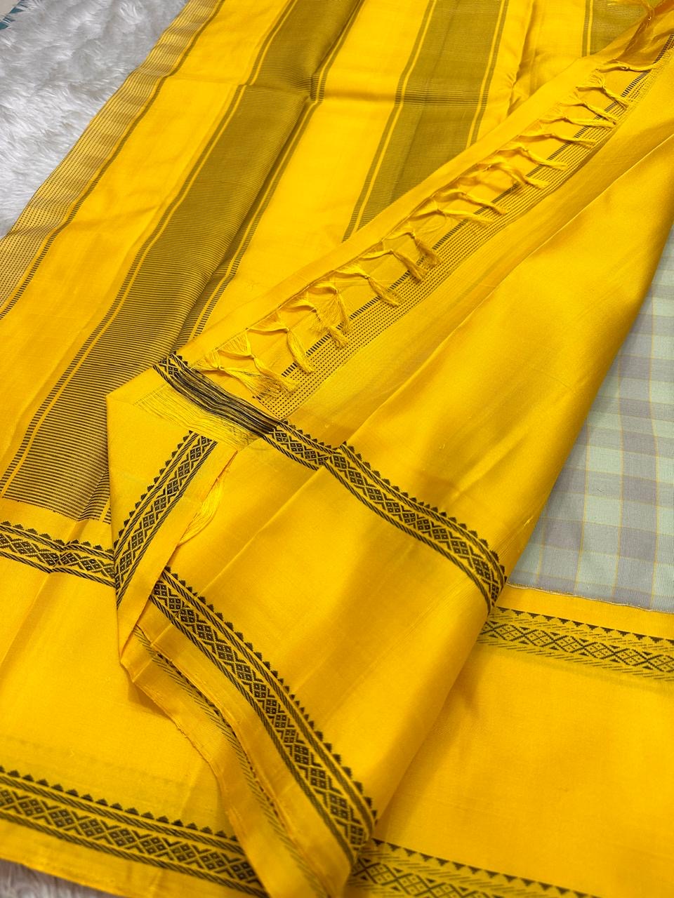 Mustard pallu of Kanchipuram silk saree with striped weave, tassels, and black zari woven border detail
Full mustard pallu laid flat with fine striped weave and zari woven edge, available in the USA