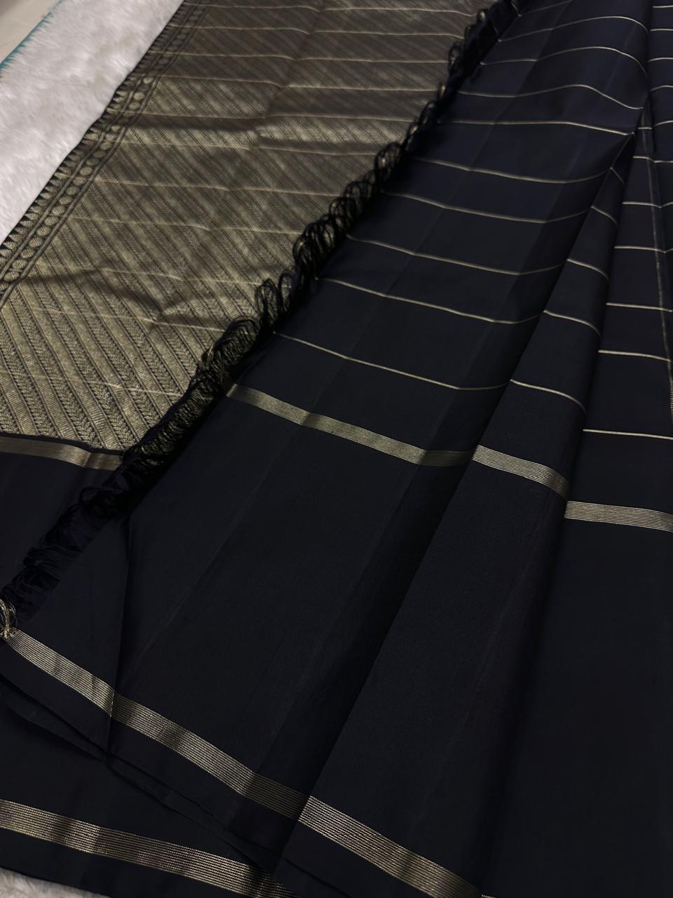 Close view of zari woven pallu section with black tassels and black saree body featuring thin zari stripe borders.
