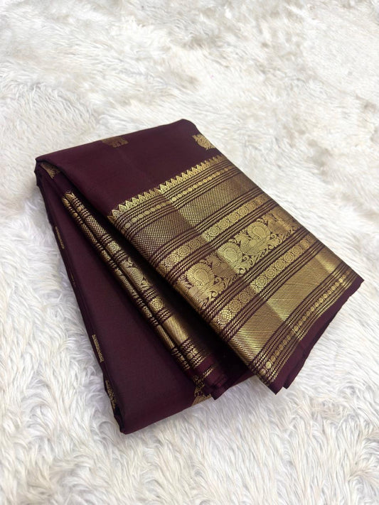 Espresso brown pure silk Kanchipuram saree with antique gold mayil chakram buttas, peacock-green detailing, and a detailed peacock and arai maadam pallu.