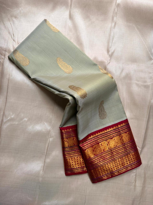 Sage green Pure Kanchipuram silk saree folded lengthwise showing maroon zari woven border panel