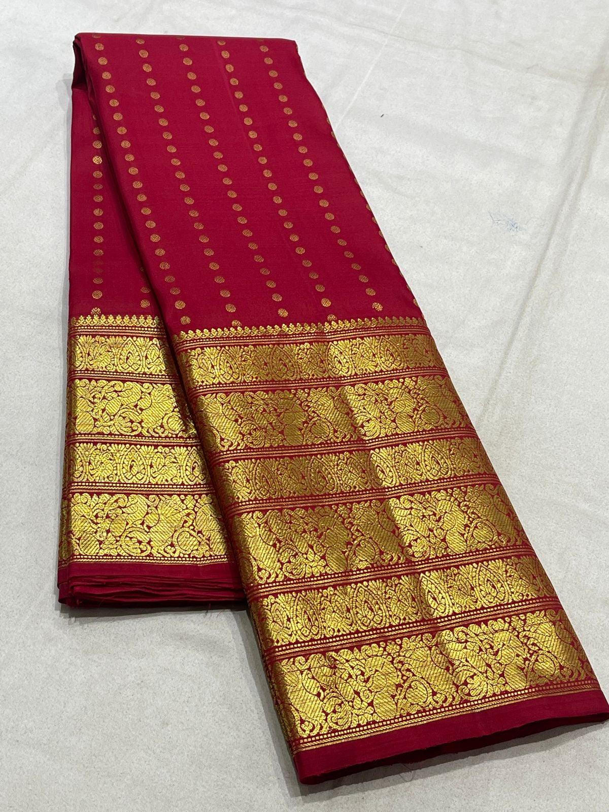 Red Kanjivaram silk saree draped view showing layered gold border and dotted zari motifs