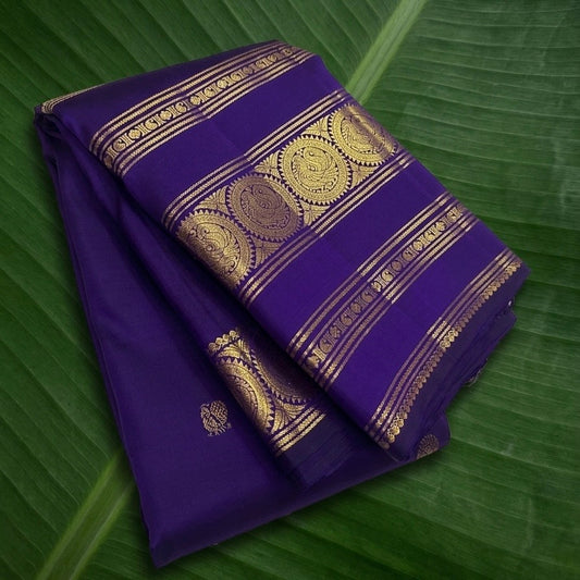 Deep violet purple Kanchipuram silk saree with traditional gold zari border folded view on white background