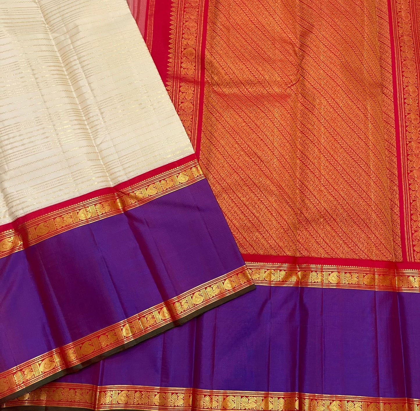 Close view of ivory body with zari stripes and contrast purple border beside orange zari woven pallu
