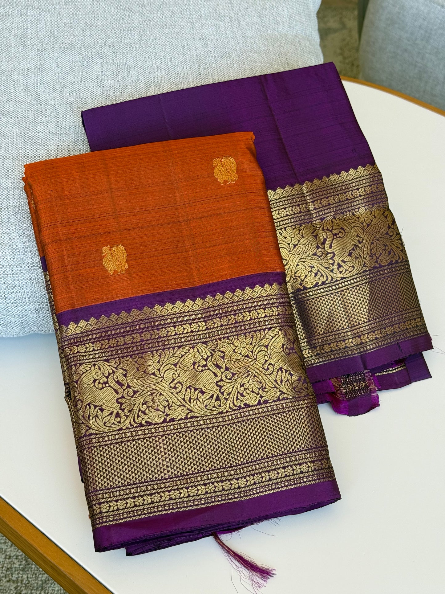 Folded view of rust orange purple Kanchipuram silk saree with intricate vanasringaram animal motifs