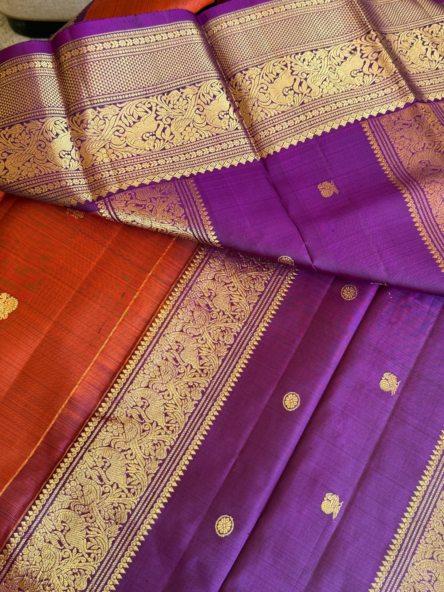 Closeup of 3g zari detailing on rust orange and purple Kanchipuram silk saree with vanasringaram design
