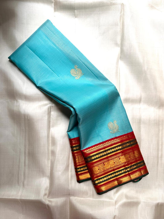 Sky blue Kanchipuram silk saree featuring classic gold zari varisaipet border and butta motifs