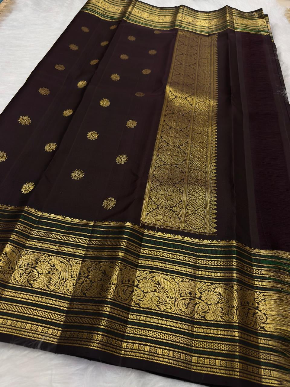 Coffee brown pure silk Kanchipuram saree with antique gold mayil chakram buttas, deep green accents, and a detailed peacock and arai maadam pallu.