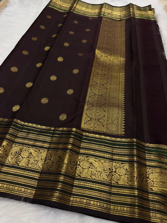 Coffee brown pure silk Kanchipuram saree with antique gold mayil chakram buttas, deep green accents, and a detailed peacock and arai maadam pallu.