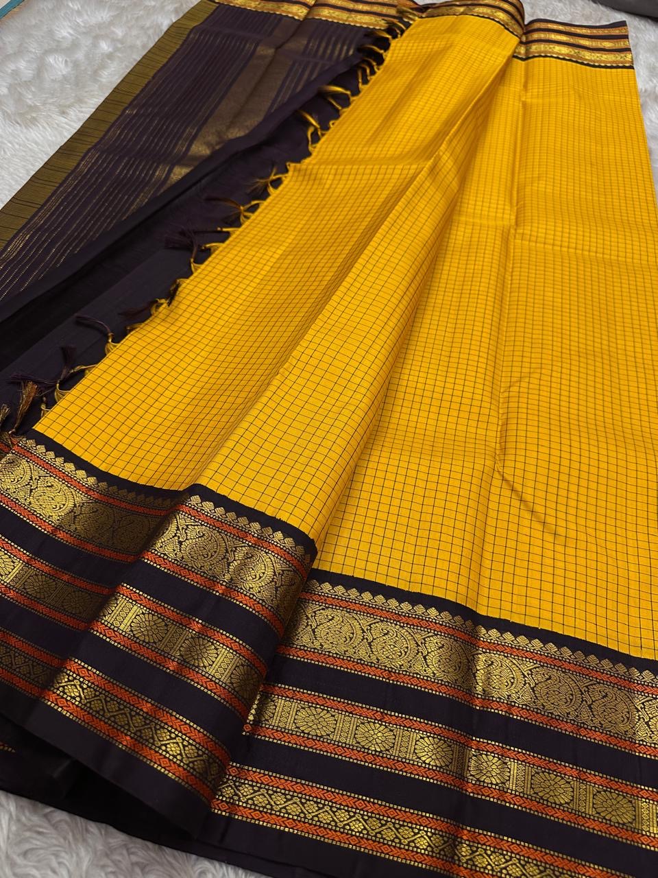 Mustard checked section of a Kanchipuram silk saree paired with a deep navy border and antique gold zari bands, shown partially spread.