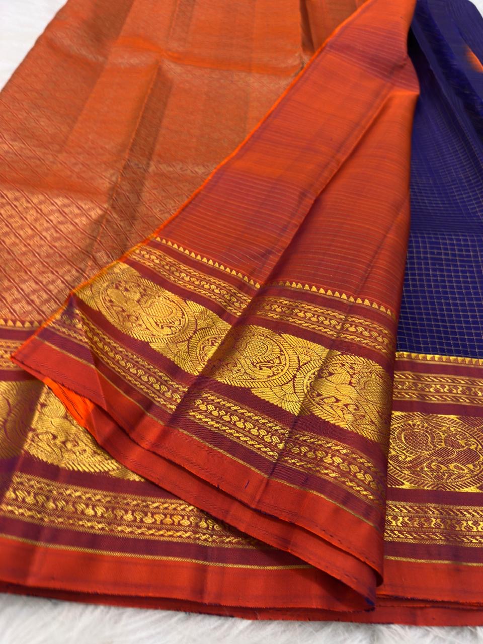 Deep Oodha blue Pure Kanchipuram Silk saree with kesari-orange Sorgavaasal Yaanai border worn at a temple vilakku puja