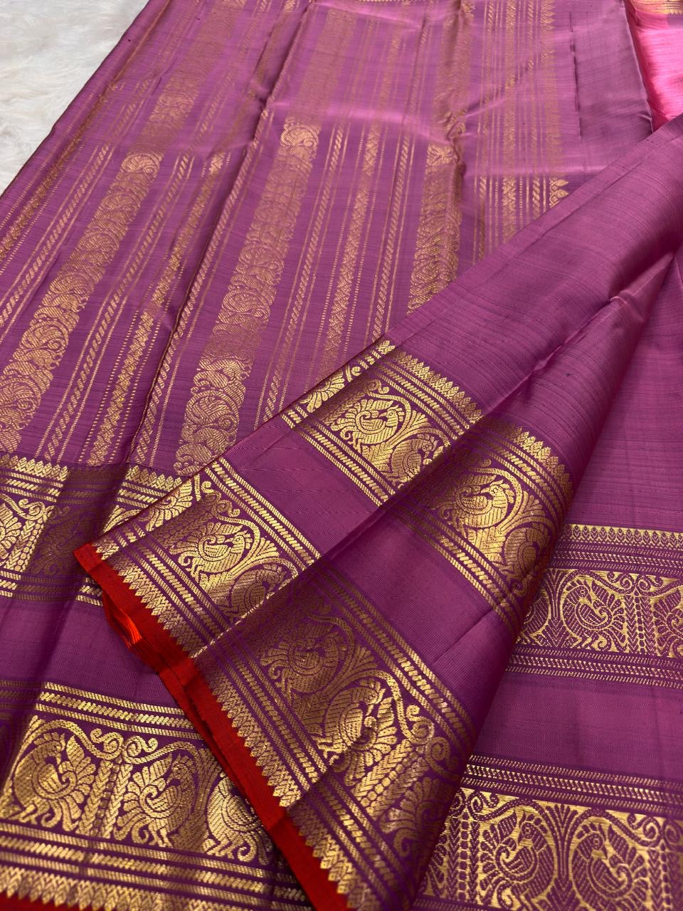 Pallu with tall zari panels, mayil-vanki motifs and kodi-malar flourishes on rose pink purple Kanchipuram saree