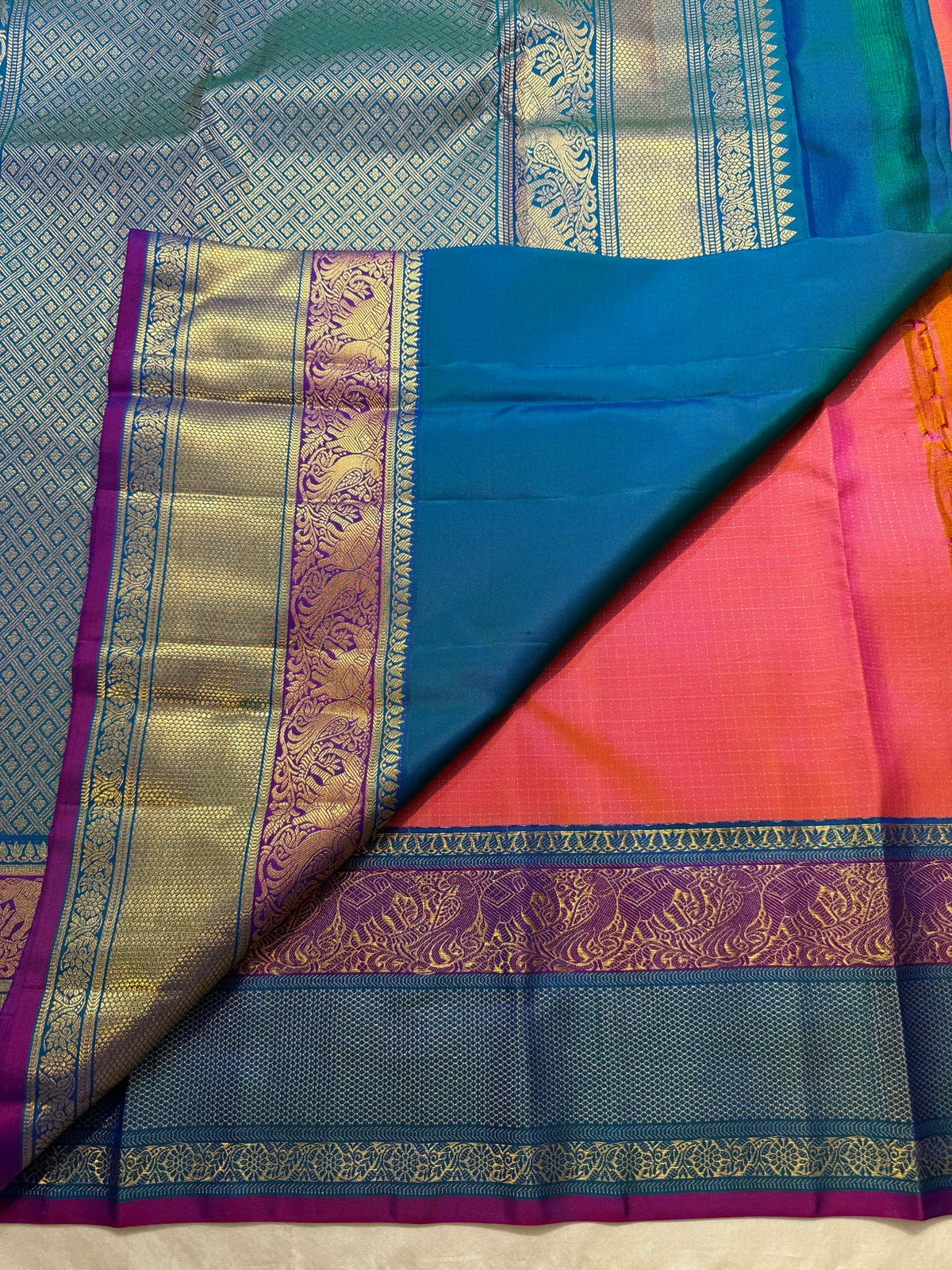 Close-up of the gold Zari Kattam grid weave on the coral-orange Kanchipuram silk saree
