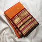 Grand red and antique gold zari pallu with ornamental bands and orange tassels.