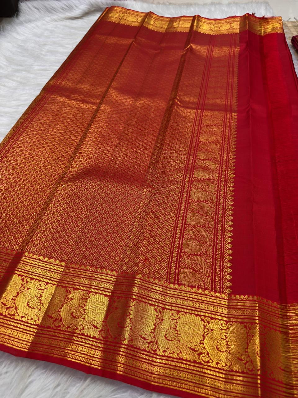 Vermilion red, warm Arakku-red undertones and rich yellow gold handwoven Kanchipuram butta silk saree, pallu full view, with gold zari detailing.