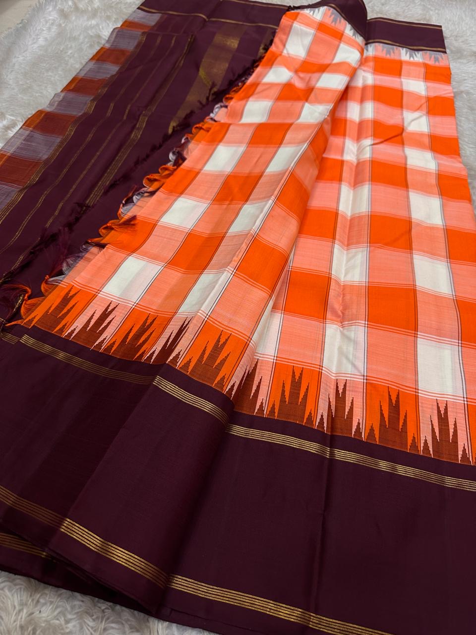 Handwoven Kesari Orange Kanchi Kattam Kanjivaram silk saree with deep purple border and gold zari pallu, worn for an Indian music school recital.