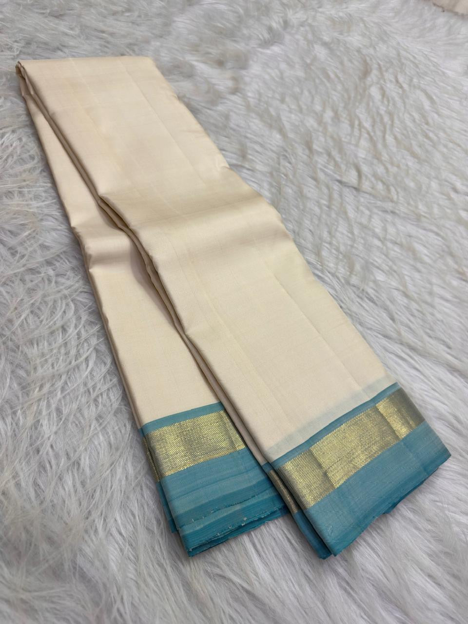 Ivory and turquoise blue Kanchipuram silk saree showing plain body, slim zari border and fine striped pallu