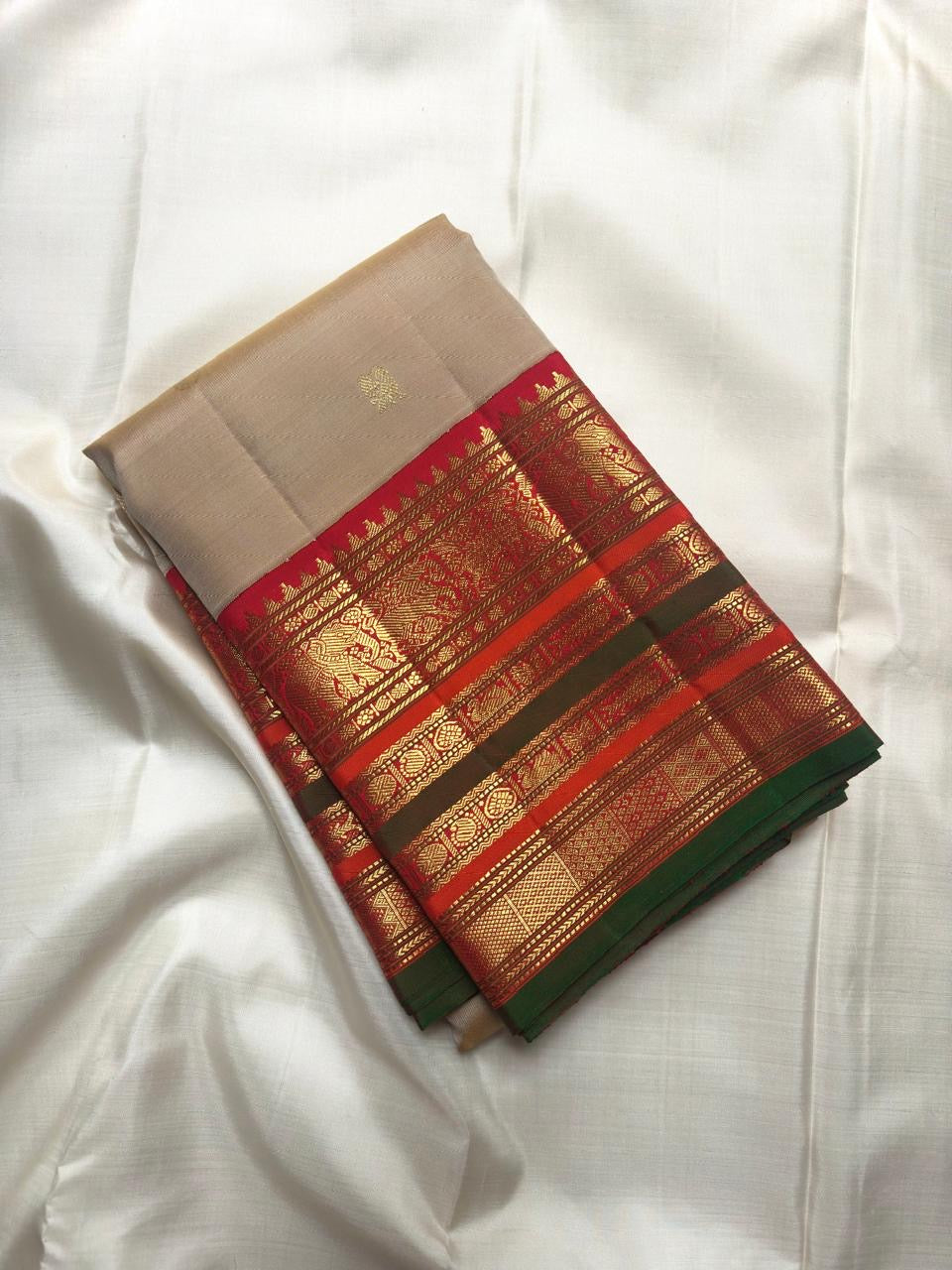 Sandalwood ivory Varisaipet Kanchipuram saree with Arakku red and emerald border detail.