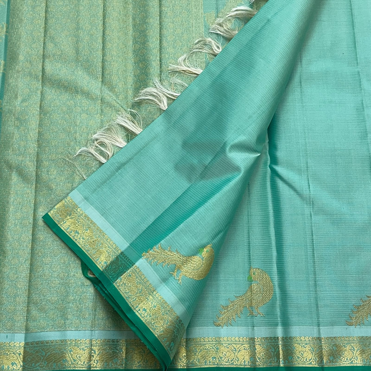 Gold zari textured pallu on seafoam green Kanchipuram silk with fine vertical woven bands and pale tassels