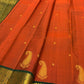 Rust orange pure silk Kanchipuram saree with small zari buttas, a bottle-green detailed paisley border, and an ornate peacock-grid kamalam pallu.