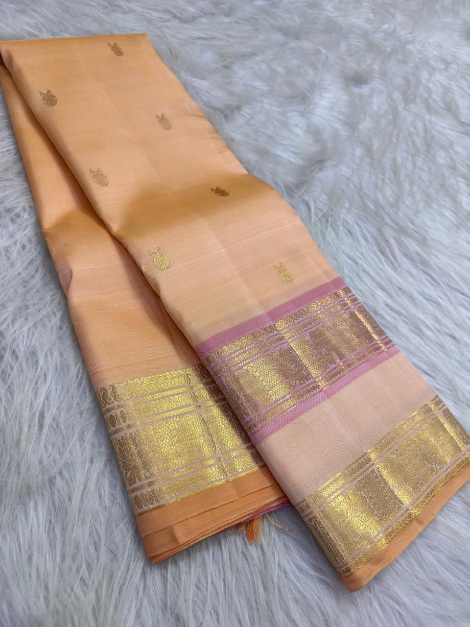 Champagne Peach and Petal Pink Pure Kanchipuram Silk Rettapet saree with ornate gold zari border, displayed in a draped front view