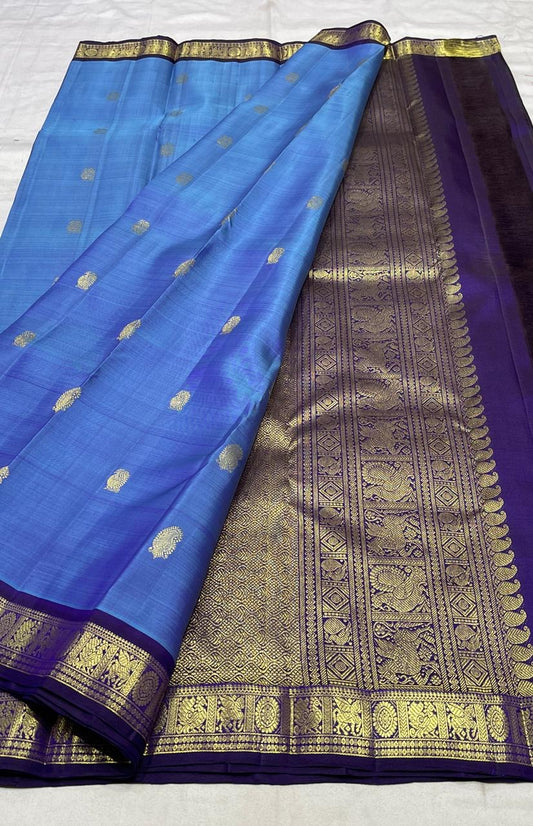 Blue Kanjivaram silk saree draped view showing purple border and traditional gold zari motifs