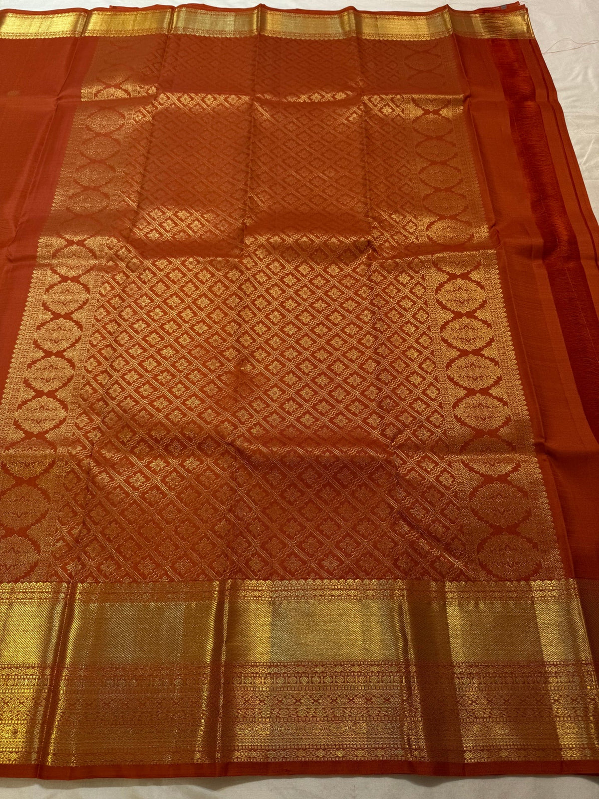 Close-up of the gold zari Butta motifs on the burnt-orange Kanjivaram silk saree