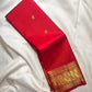 Vermilion red, warm Arakku-red undertones and rich yellow gold handwoven Kanchipuram butta silk saree, folded front, with gold zari detailing.