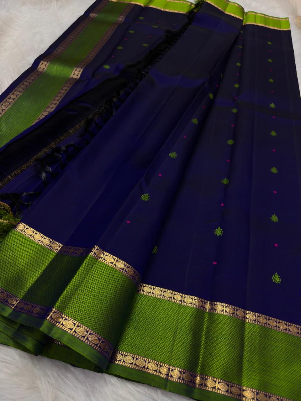 Karu Neelam silk body with green silk-thread buttas scattered across the open field and pink pinpoint accents.