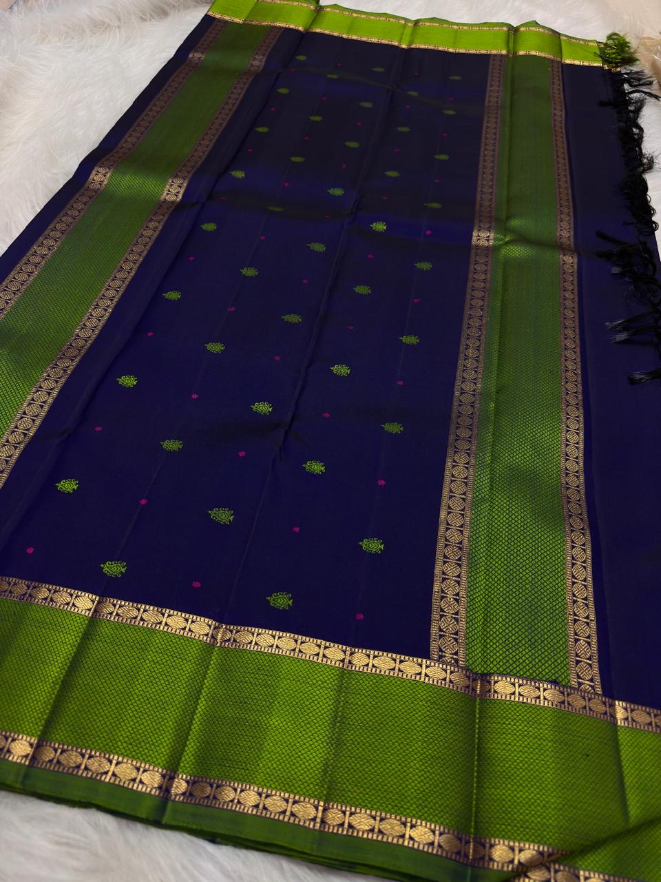 Karu Neelam pure silk Kanchipuram Butta saree with green silk-thread motifs and vivid Ilai Pachai zari border.